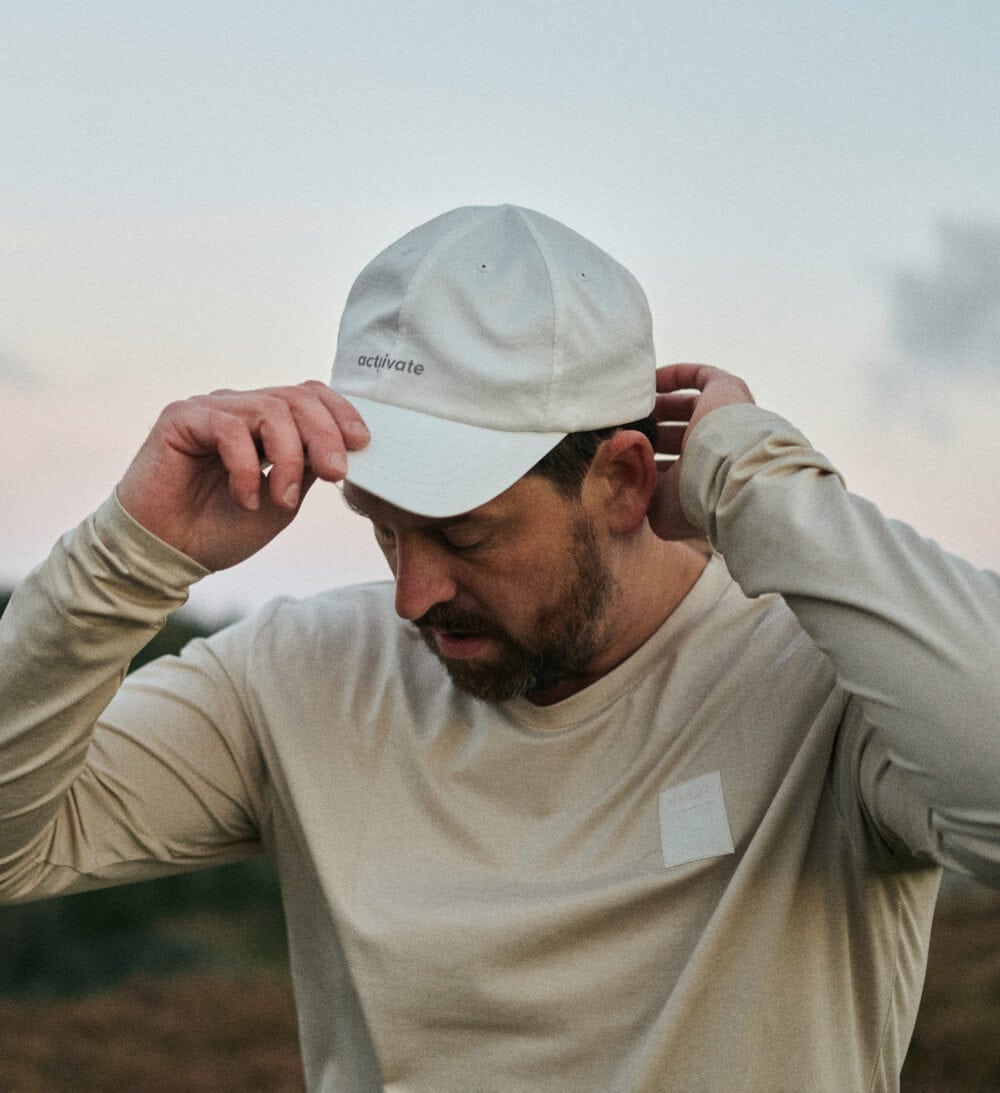 Man dressed in white putting on his cap at sunrise